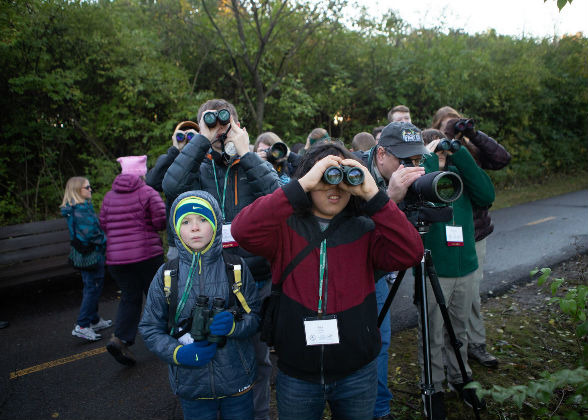 Photo of young birders dressed warmly, most looking through binoculars.
