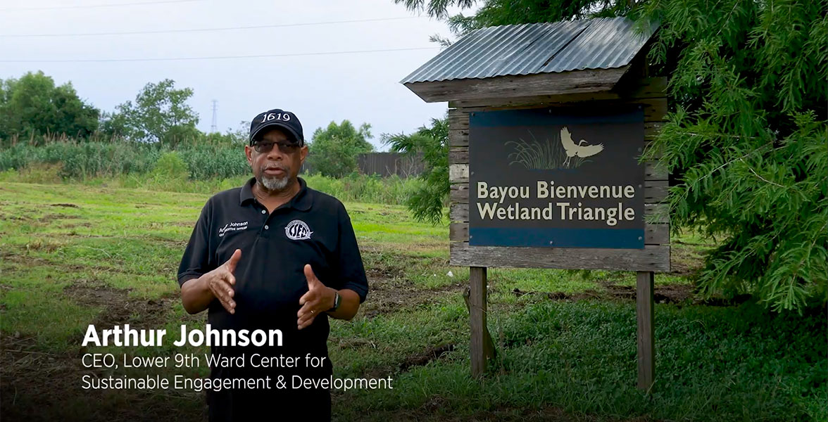 Arthur Johnson, CEO of the Lower 9th Ward Center for Sustainable Engagement and Development, stands next to the Bayou Bienvenue Wetland Triangle sign.
