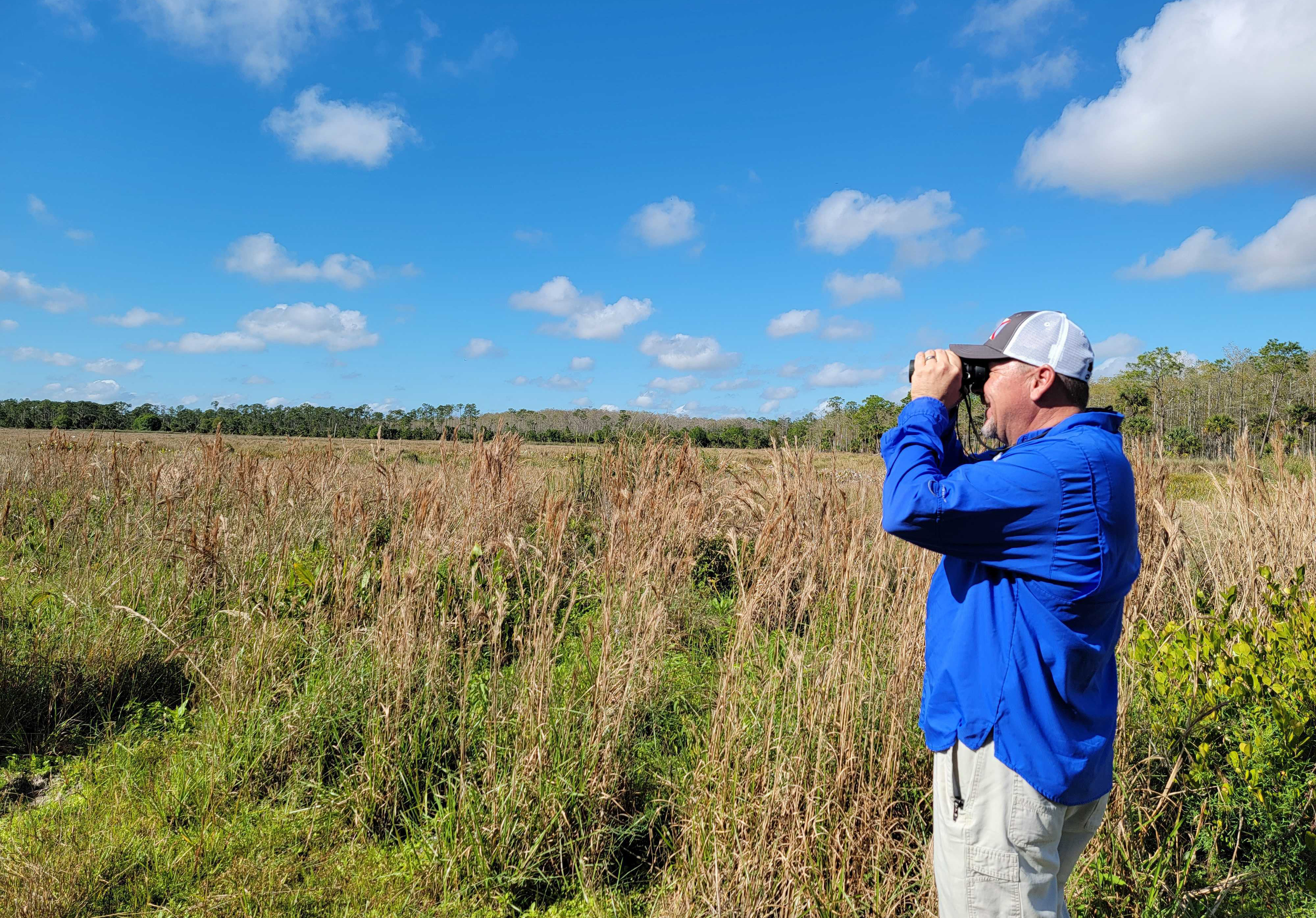 A man in a field with binoculars.
