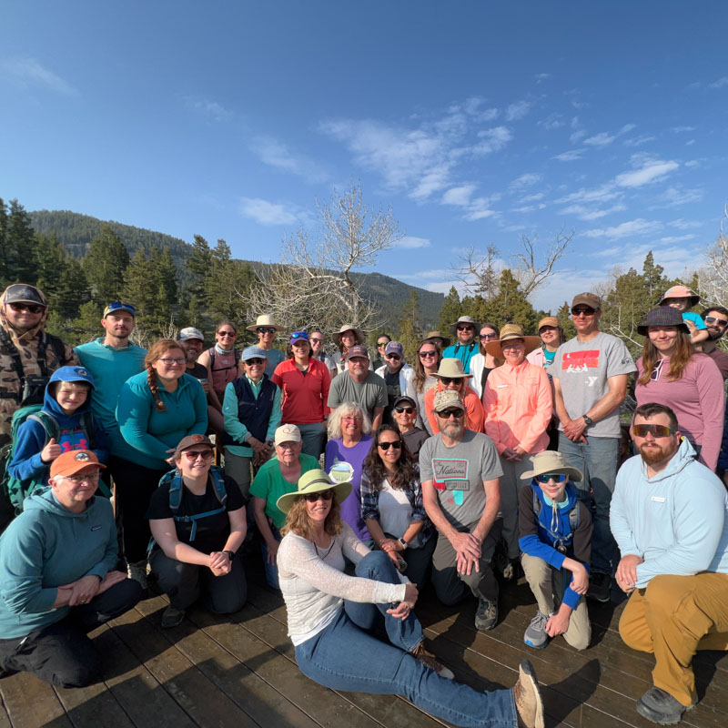 A group of three-dozen people pose outdoors for a photograph.