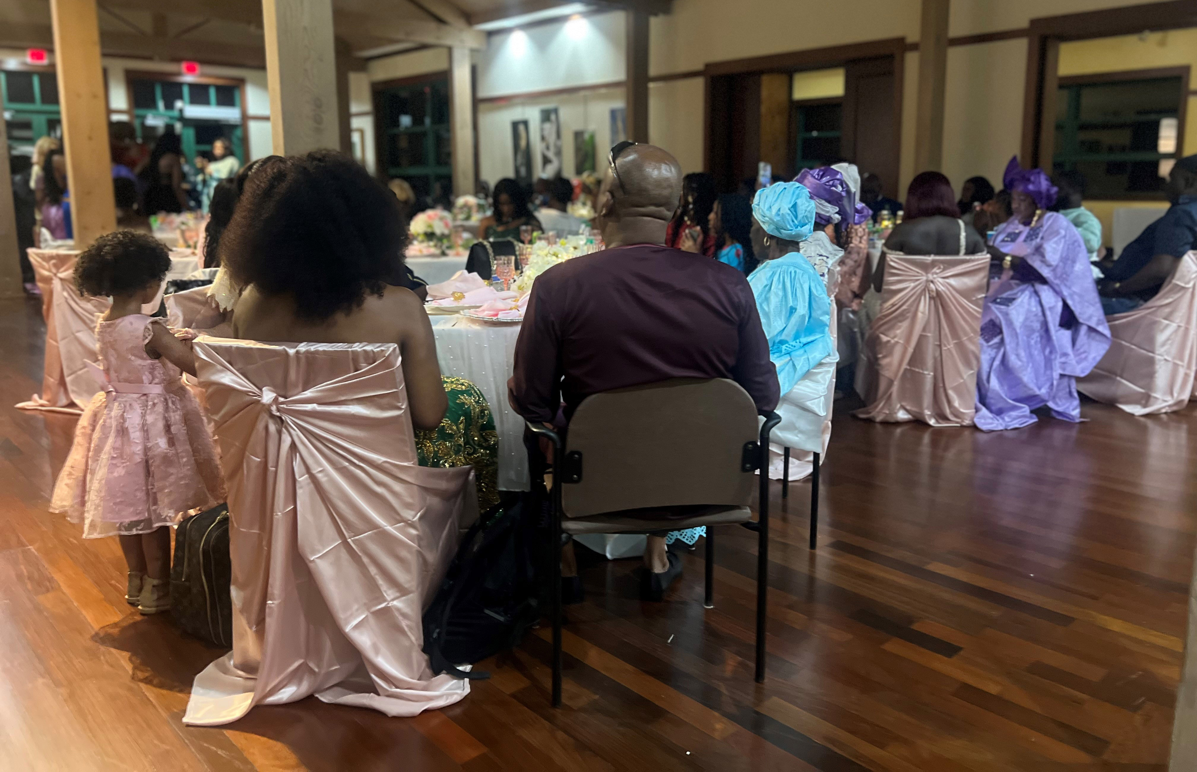 Room where people dressed in bright colors are seated at tables.