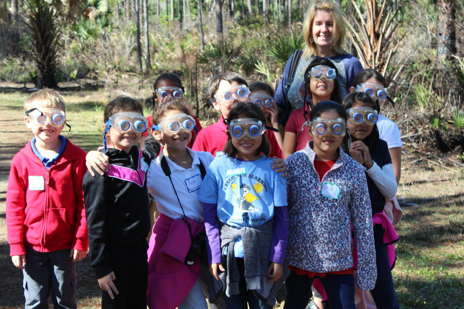 A group of students wearing goggles standing outdoors with their teacher.