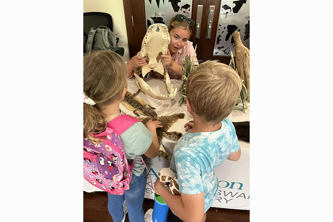 An educator holds artifacts for children to see