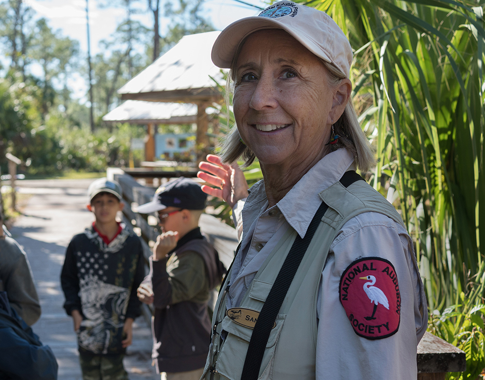 A woman wearing a uniform directing students outdoors