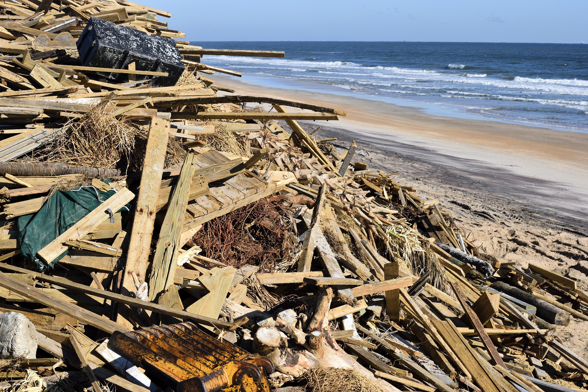 Hurricane debris piled up on a beach, with the ocean in the background.