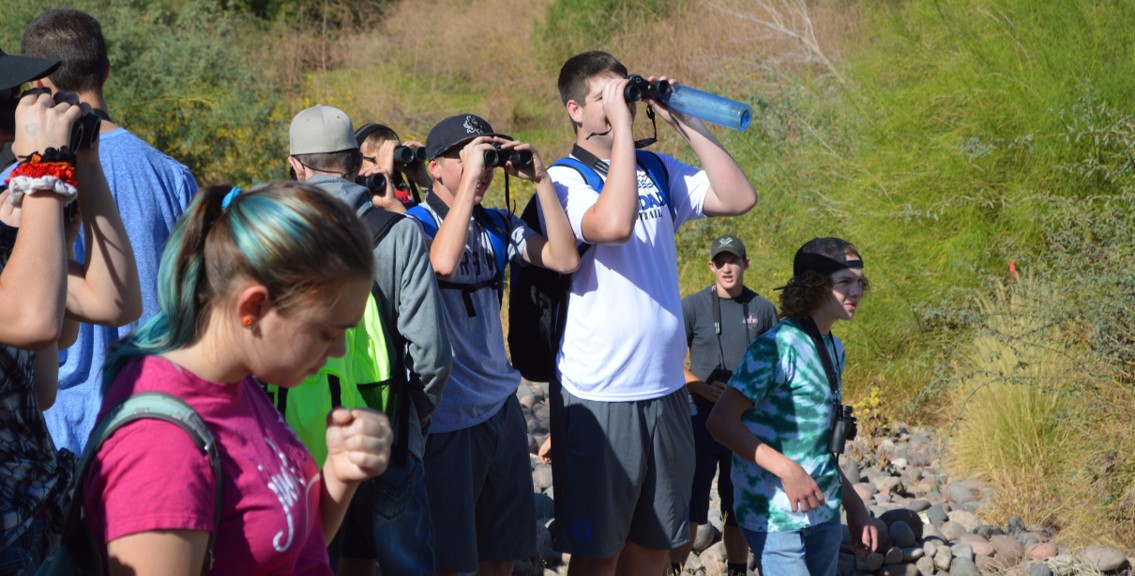 Teens look out at the Salt River with their binoculars.