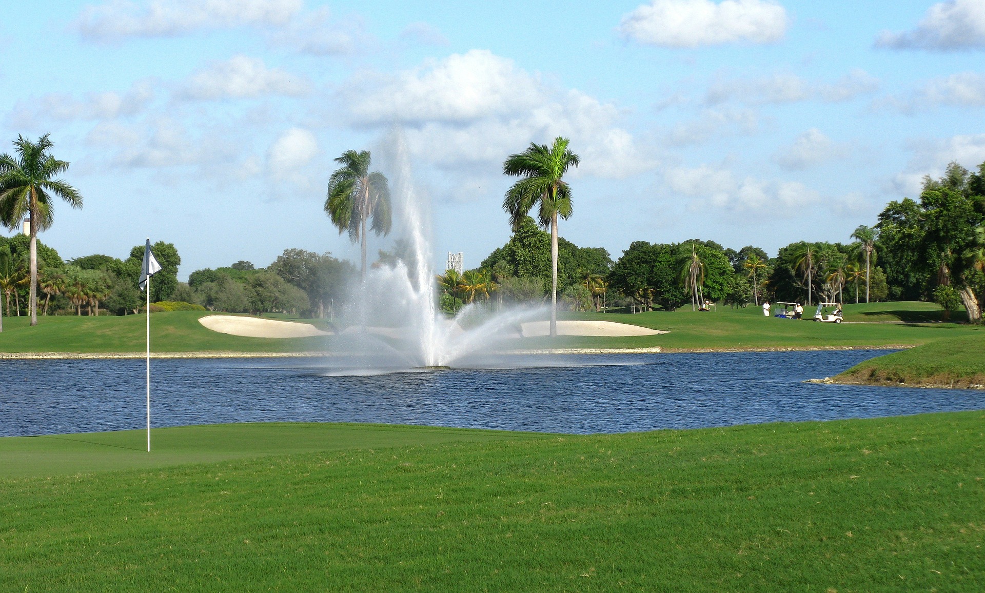 Golf course with fountain spraying water from a pond.