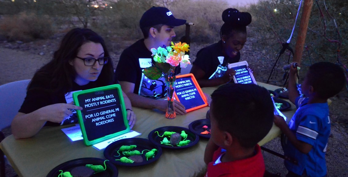 A woman points at a sign for a child to learn about the diet of an animal.