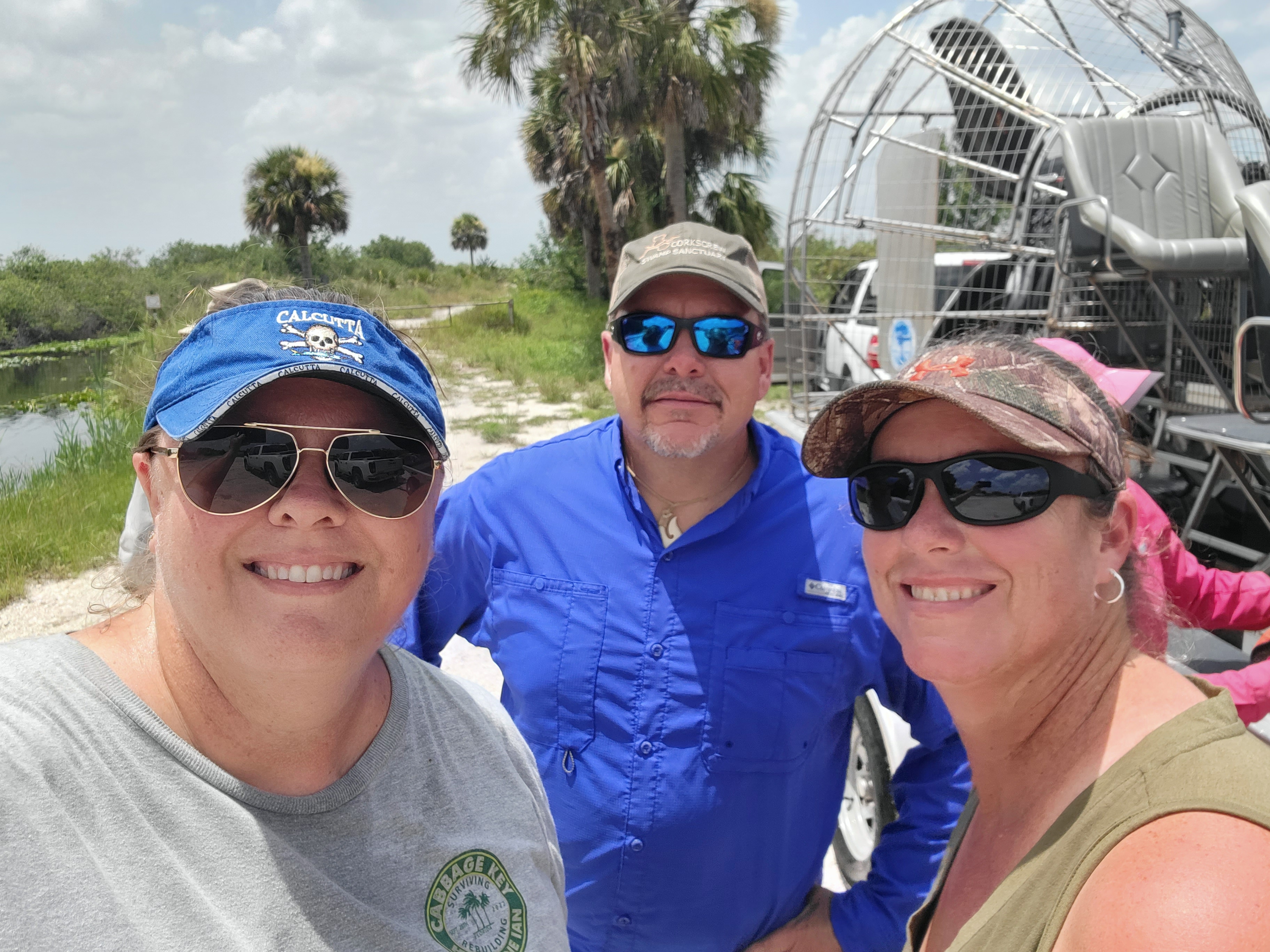 Three people standing in front of an airboat