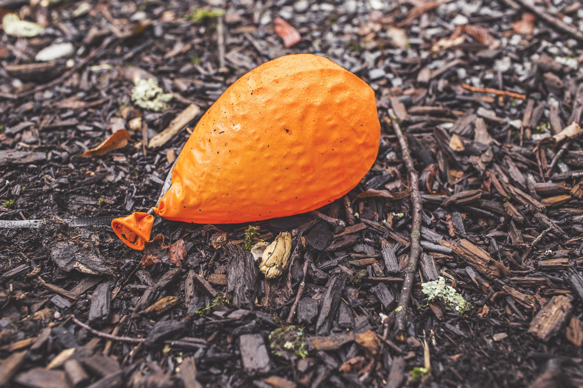 Deflated orange balloon on the ground.