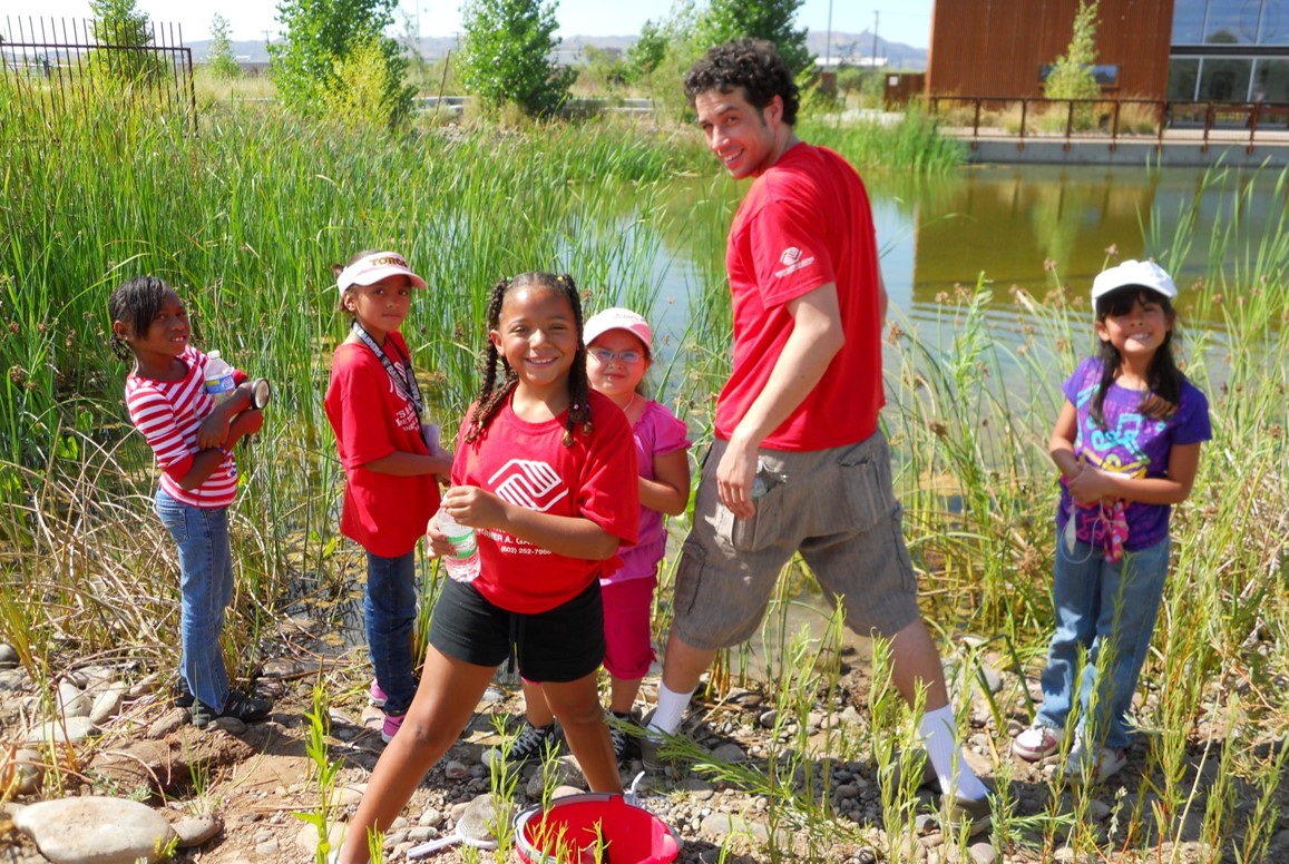 A group of people standing next to the pond.