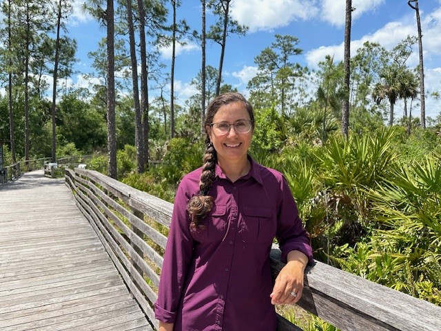 A woman standing on a boardwalk smiling for the camera