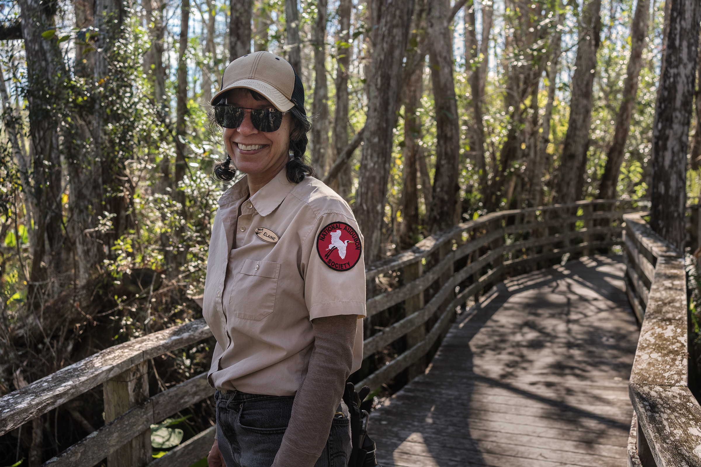 Photo of a female volunteer naturalist wearing a uniform on the boardwalk 