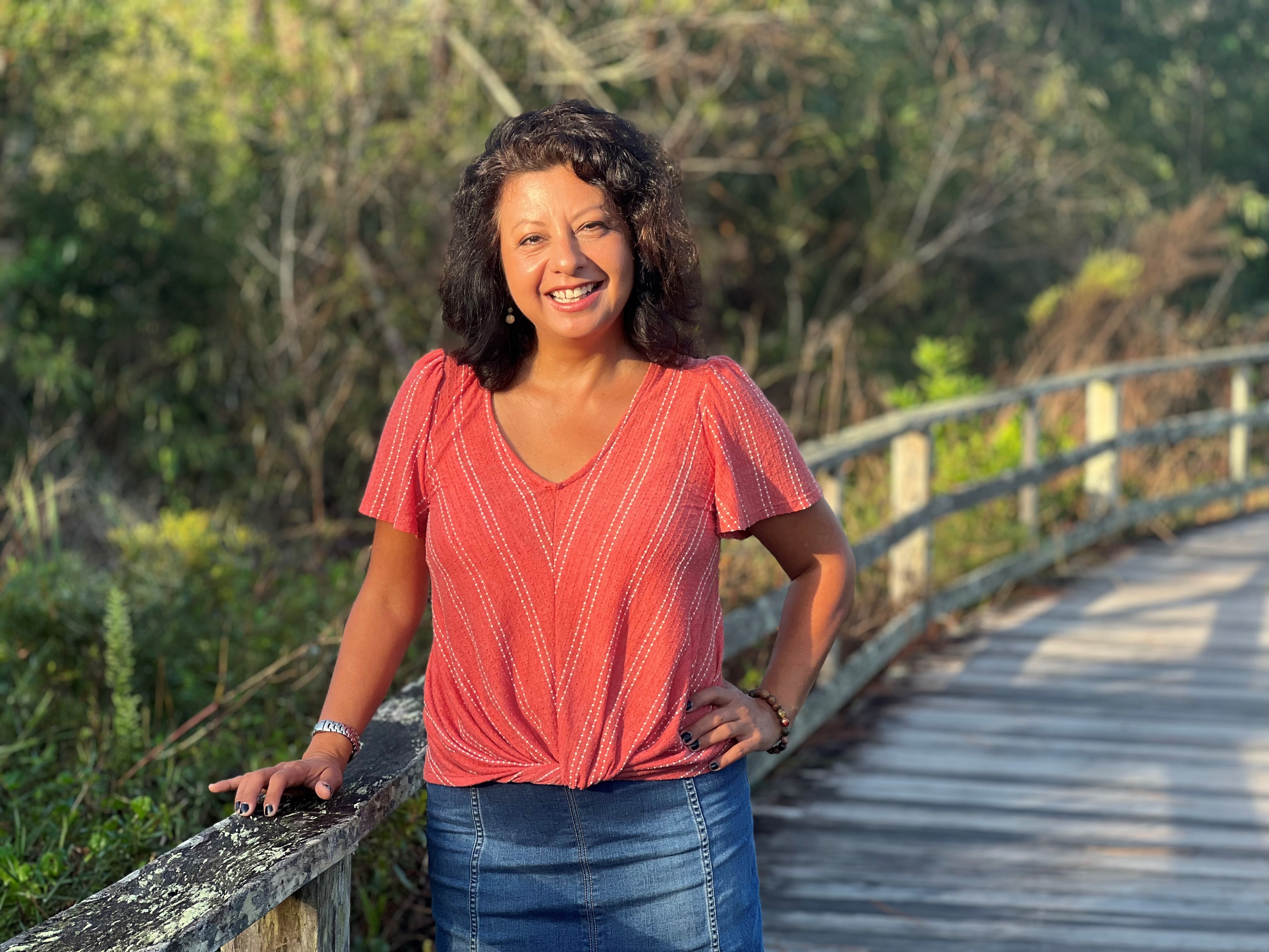 A smiling woman on a boardwalk in the forest