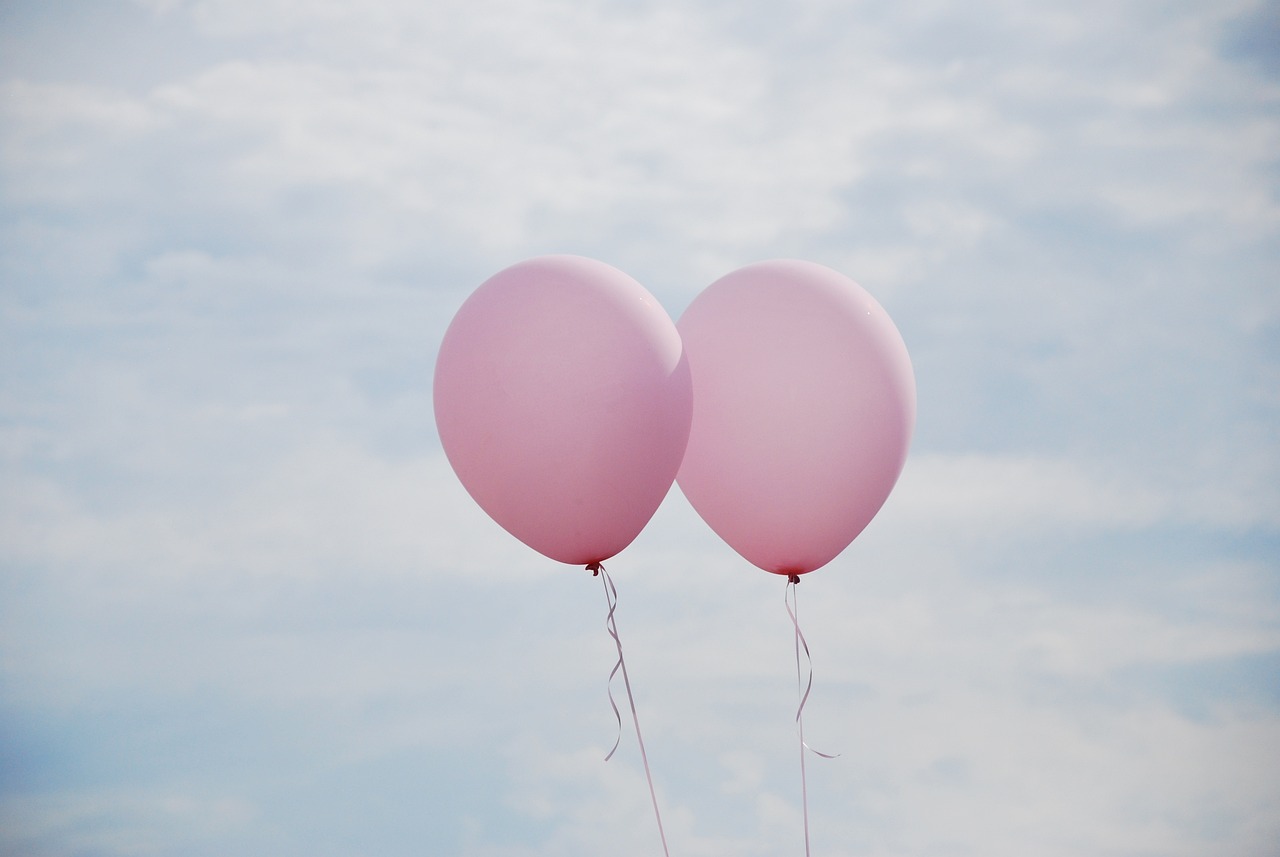 two pink balloons in the sky