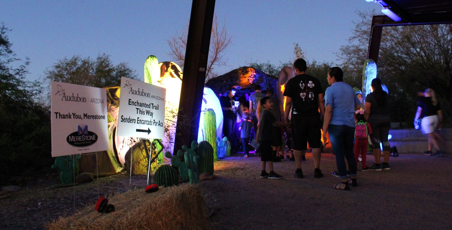 People walking into a colorfully lit cave.