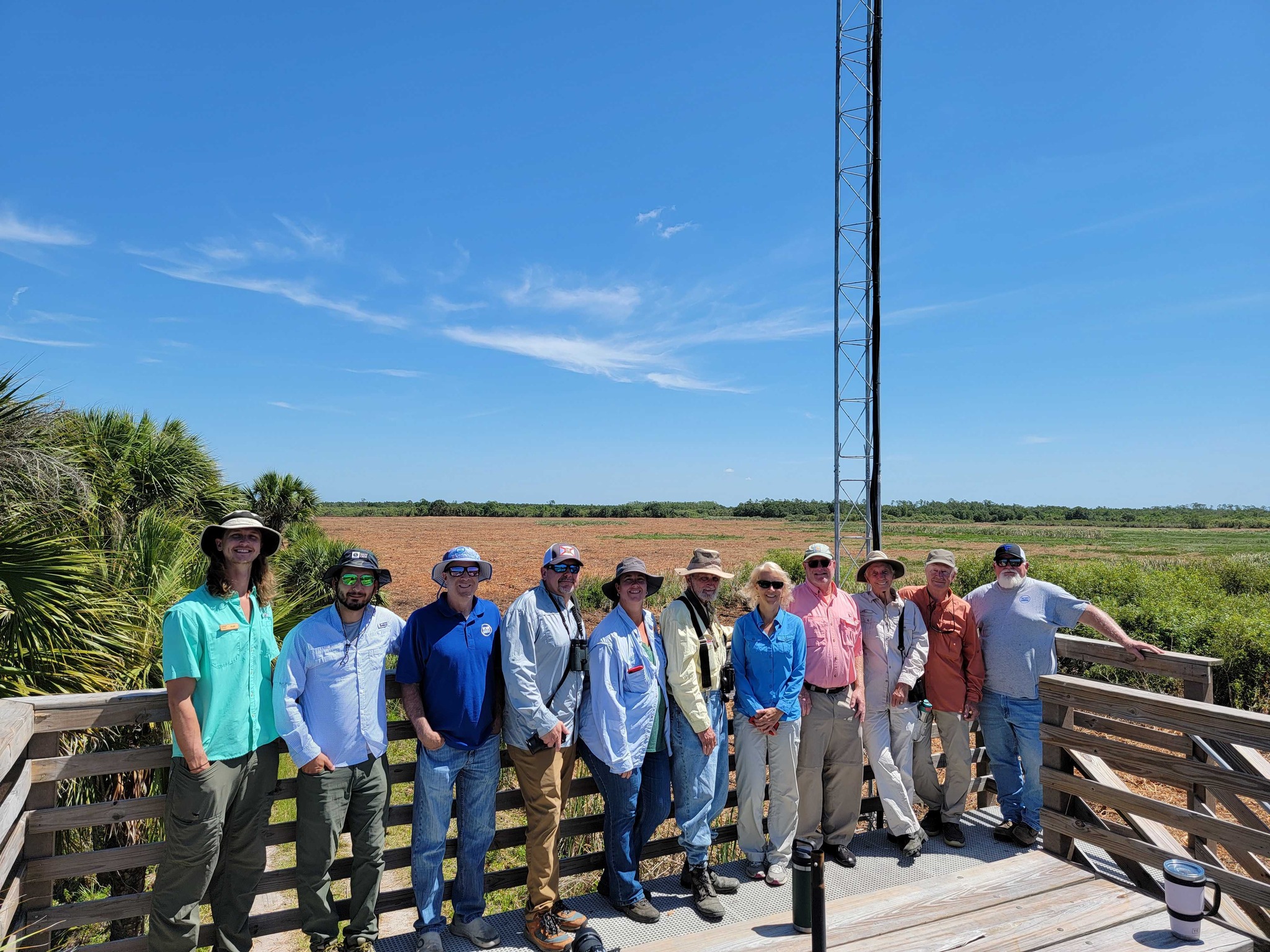 A group of people standing on a platform with blue sky and an antenna