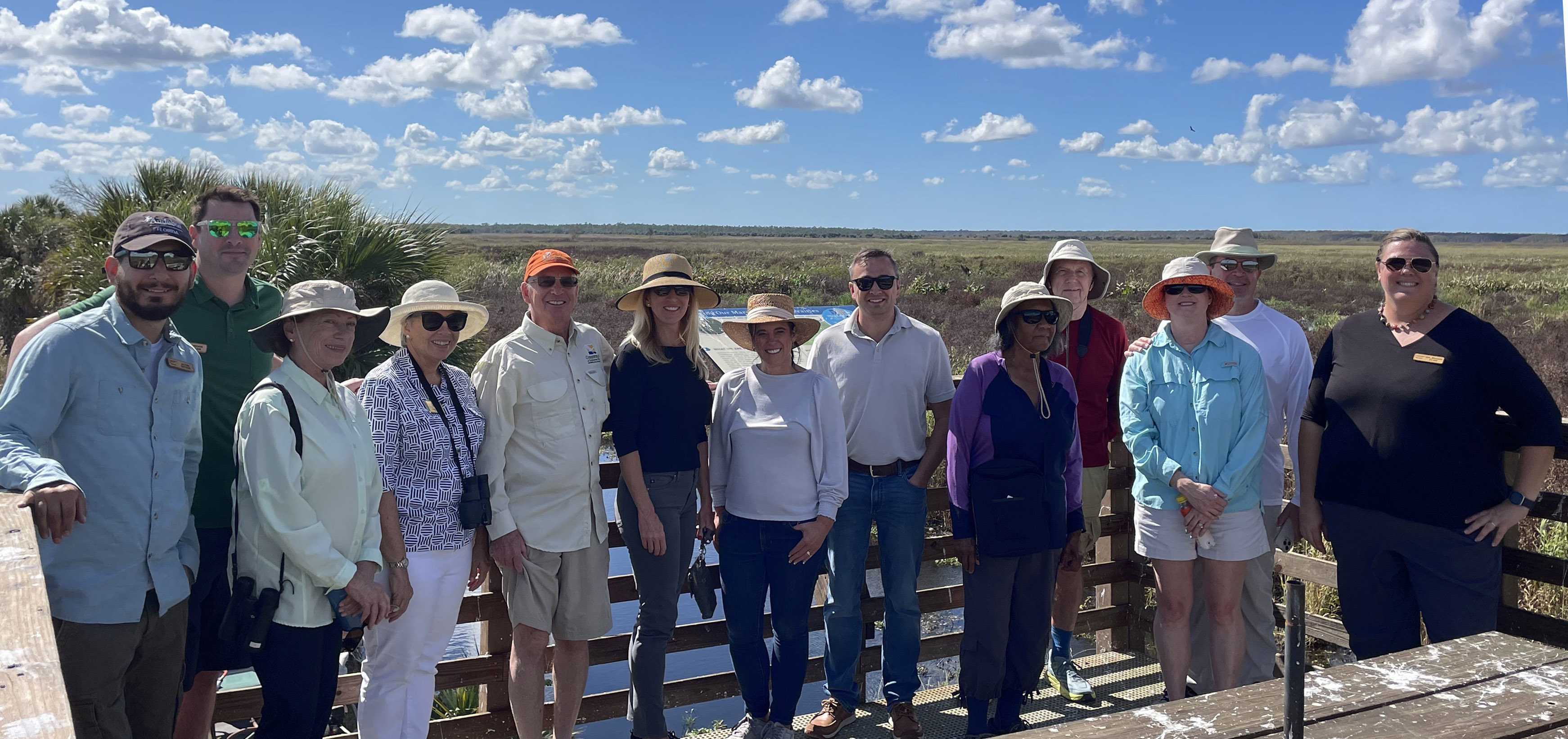A group of people posing on a platform overlooking a wetland.