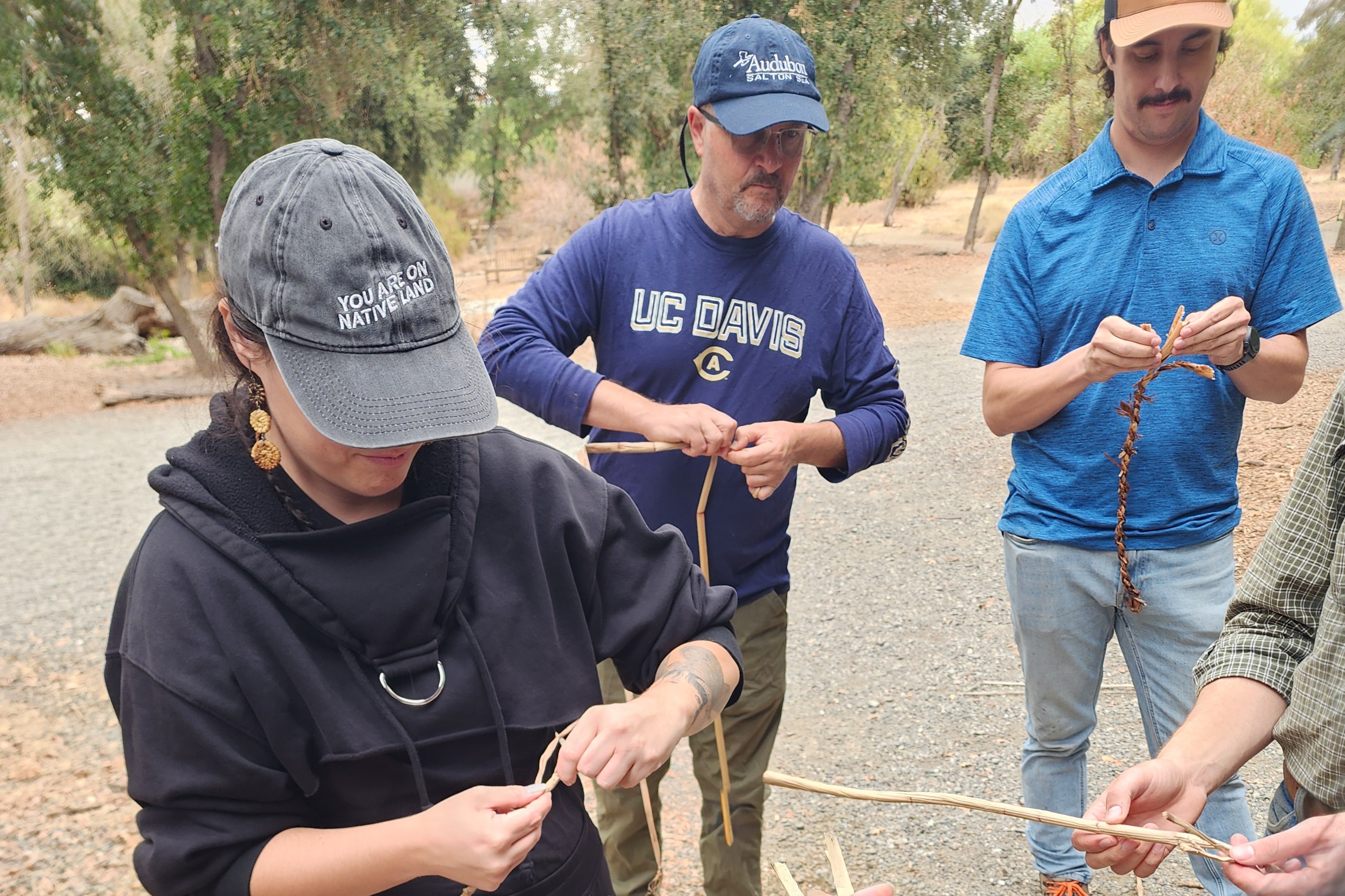 Audubon CA staff members Lindsay Rowe (Salton Sea and Desert), Pelayo Alvarez (Conservation Ranching), and Ian Souza-Cole (Working Lands) learn to weave tule, an ecologically and culturally significant sedge native to freshwater marshes.