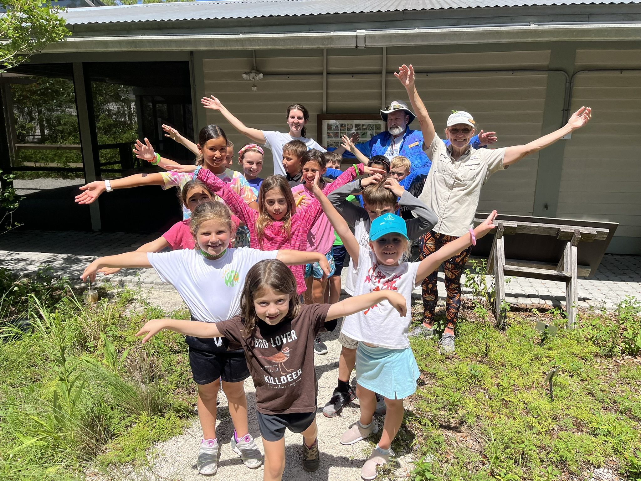 A group of smiling children standing with their arms outstretched