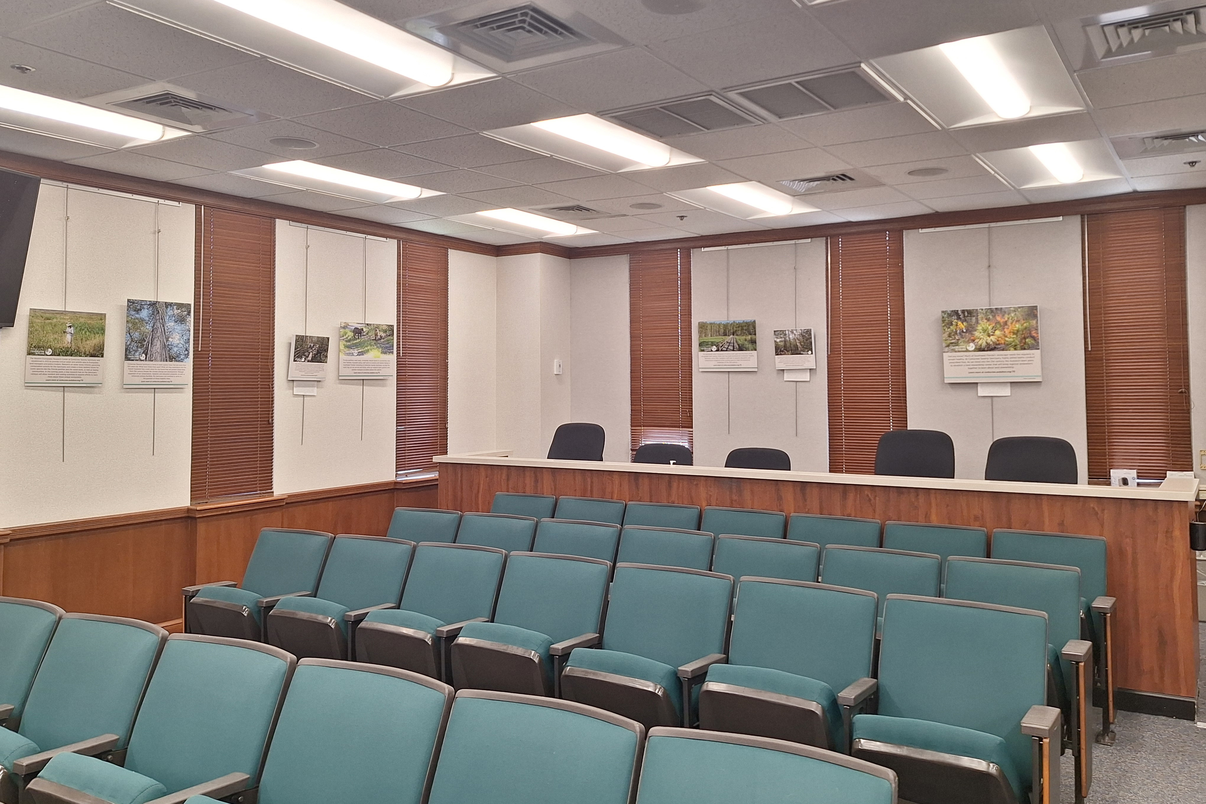 A room with empty seats and photography on the back wall. 