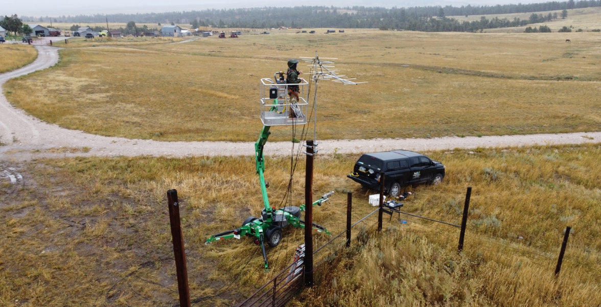 An individual on a boom lift installs Motus radio antennas.