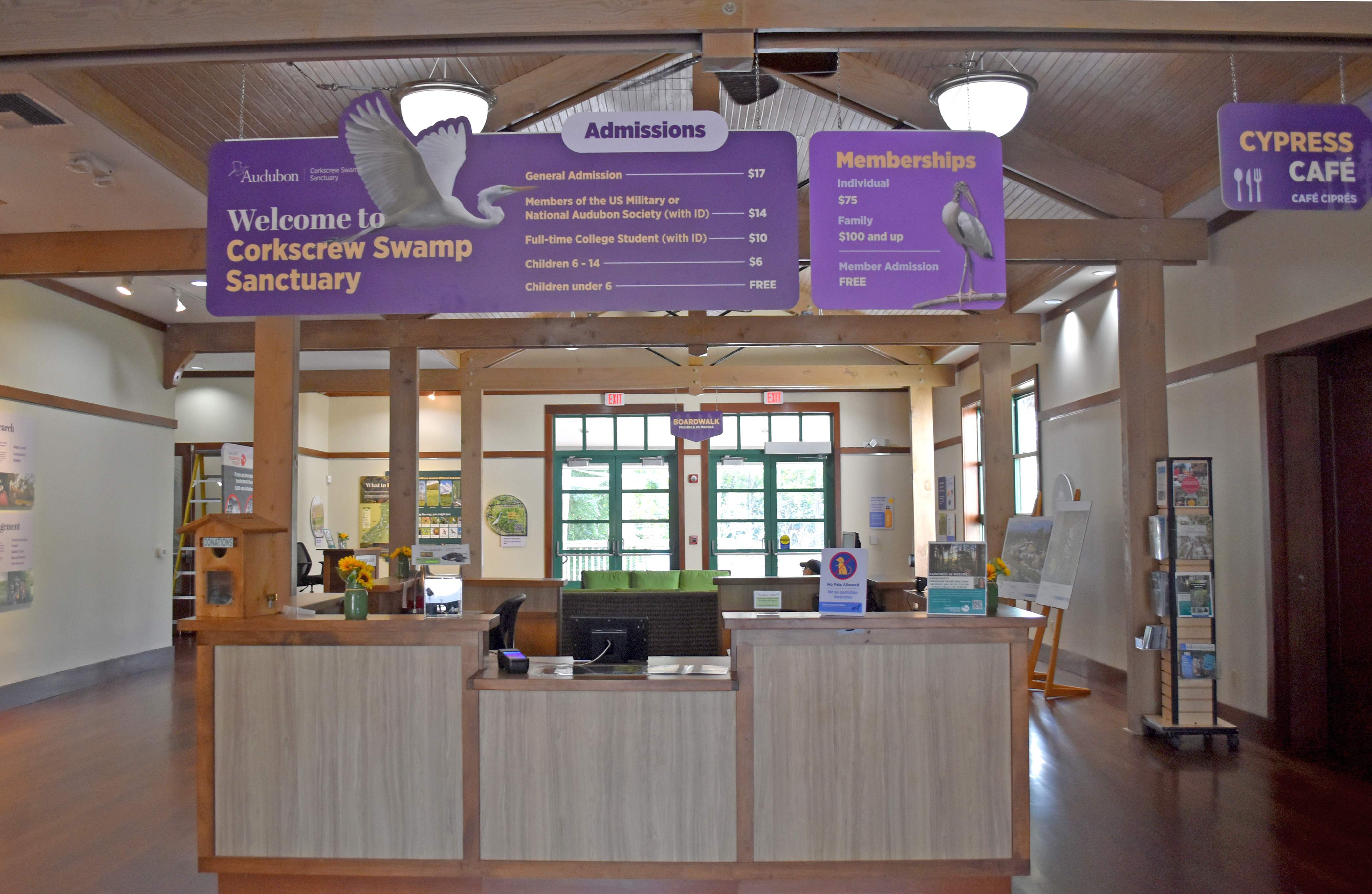 Photo shows an admissions desk with purple signs overhead announcing admissions information